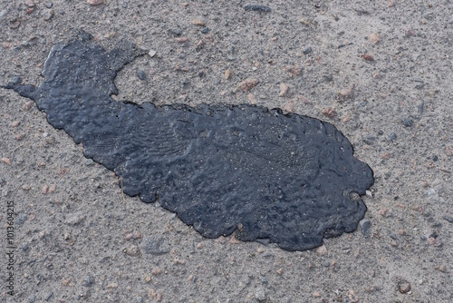 one big black spot of resin on the gray asphalt of the road on a summer city street photo