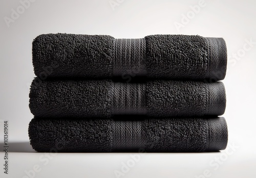 Three black towels stacked on top of each other, against a white background 