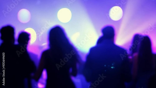 Silhouettes of people dancing in a club with light effects and soft bokeh.