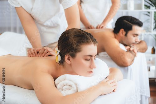 Caucasian couple customer enjoying relaxing anti-stress spa massage and pampering with beauty skin recreation leisure in day light ambient salon spa at luxury resort or hotel. Quiescent