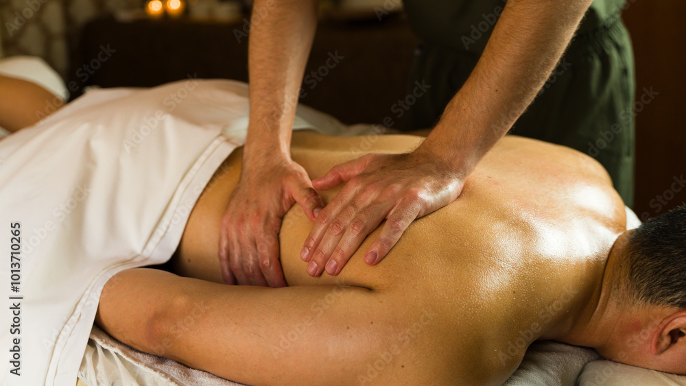 Man receiving a soothing back massage from a male masseur on a massage table in a spa