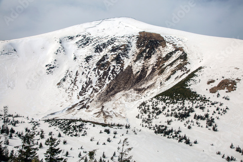 A dramatic avalanche scar gouges a snow-covered mountainside photo