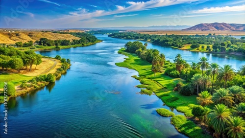 The majestic Nile River gracefully flows through lush greenery, embraced by a bright blue sky, offering a serene tableau of nature's breathtaking splendor.