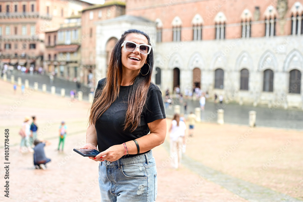 Obraz premium Happy smiling woman using a phone at Piazza del Campo ,at Siena , Tuscany Concept of Italian gastronomy and travel.