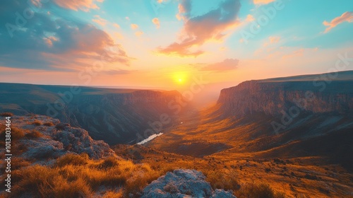 A stunning sunset over a vast canyon with a river winding through the valley, casting a warm glow over the landscape.