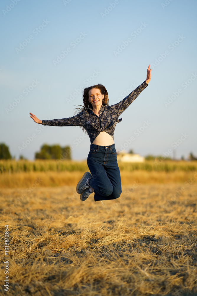 A Joyful Young Woman Happily Jumping in a Beautiful Golden Field Under the Sunlight A Joyful Young Woman Happily Jumping in a Beautiful Golden Field Under the Sunlight