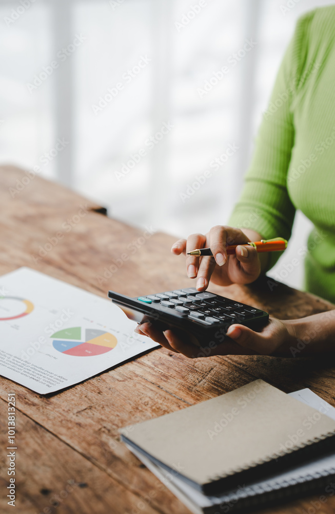 Fototapeta premium Close-up of young woman's hand working with tax and accounting documents using laptop and calculator to calculate financial transactions, taxes, company income. Finance and tax concepts