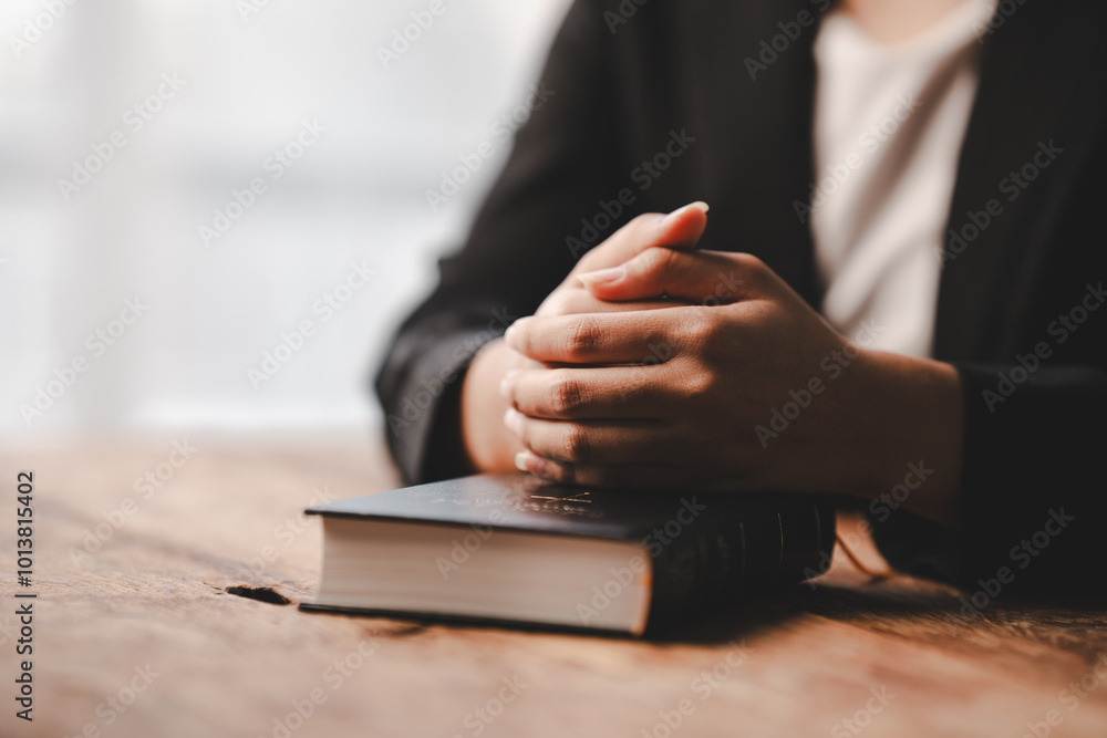 Cropped view of young woman praying with bible on table Confession concept Pray and talk with God Cropped view of young woman praying with bible on table Confession concept Pray and talk with God