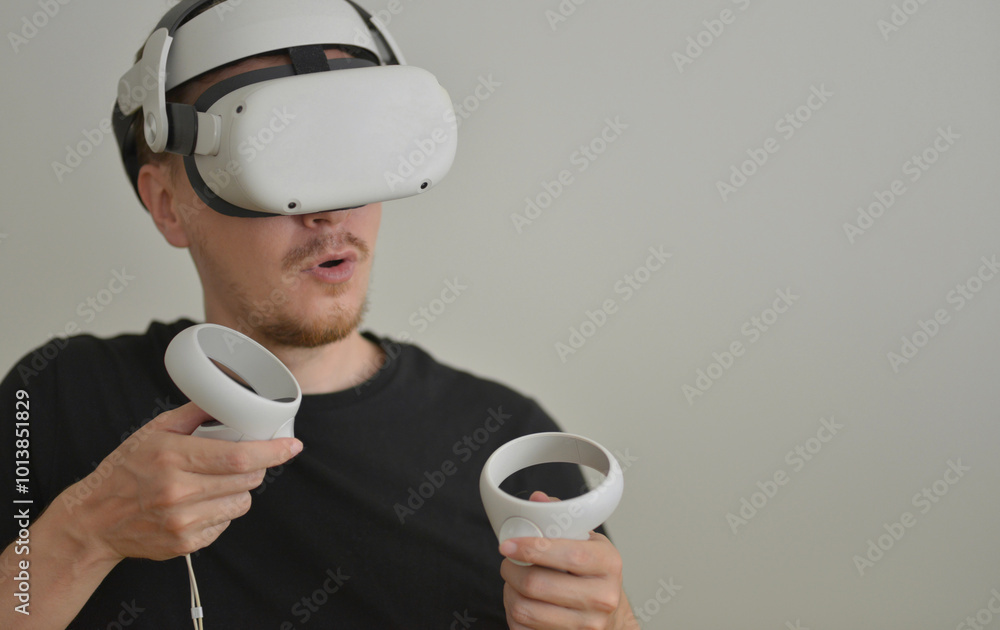 A Young Man Playing using Visual Reality Glasses with Joysticks with Copy Space. VR Headset Goggles Connecting Metaverse. Futuristic Cyberspace Technology, Virtual Digital Environment Concept A Young Man Playing using Visual Reality Glasses with Joysticks with Copy Space. VR Headset Goggles Connecting Metaverse. Futuristic Cyberspace Technology, Virtual Digital Environment Concept