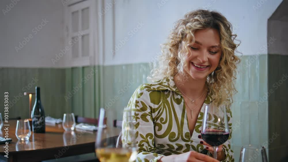 Two women drinking wine laughing looking cellphone in cozy restaurant closeup. Two women drinking wine laughing looking cellphone in cozy restaurant closeup.