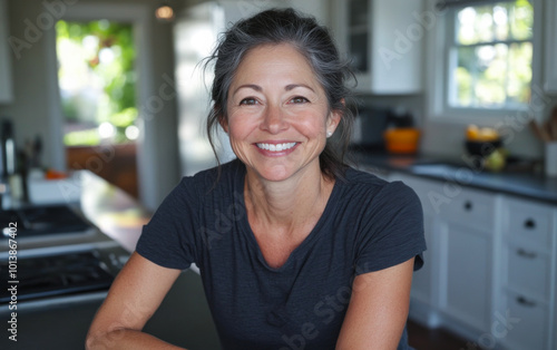 A middle-aged woman smiles warmly in a bright, inviting kitchen while preparing a meal