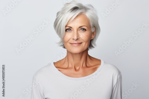 Beautiful mature woman. Portrait of beautiful mature woman looking at camera and smiling while standing against grey background