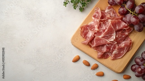 A wooden board with jamon and manchego cheese, isolated on a light stone background with fresh grapes and almonds photo