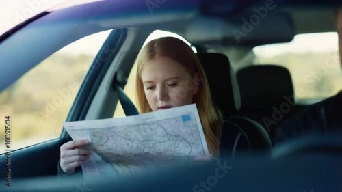 Young woman looking city map sitting on car at street
