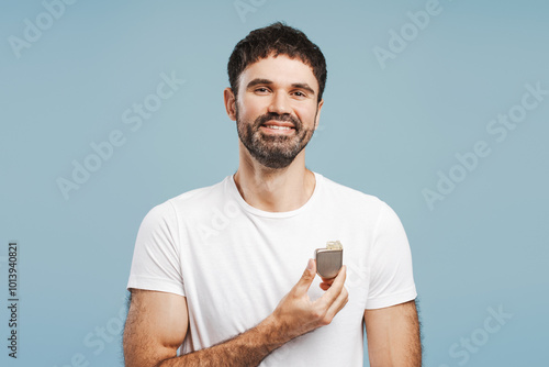 Smiling, bearded man holding pacemaker looking at camera. Patient showing cardioverter defibrillator photo