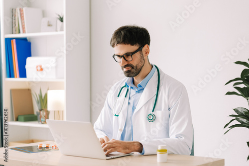 Professional doctor wearing white coat and stylish eyeglasses, sitting on workplace in modern clinic