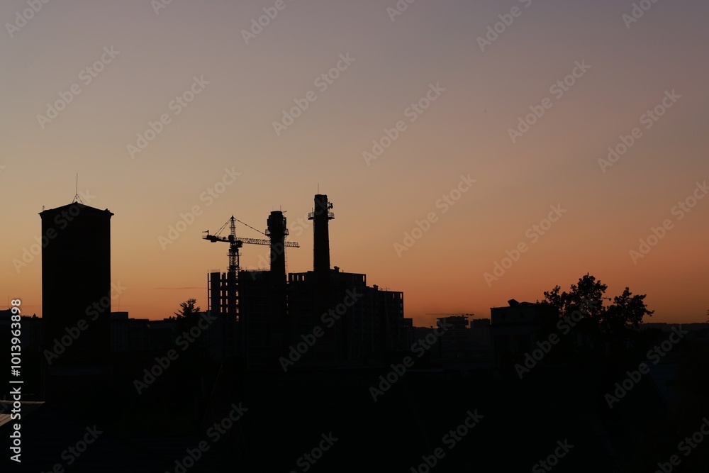Buildings, tower crane and trees under beautiful sky in evening Buildings, tower crane and trees under beautiful sky in evening