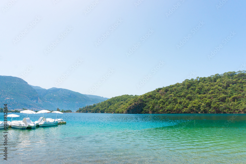 View of Blue Lagoon with Sun Loungers and Umbrellas Along a Tropical Beach on a Clear Summer Day View of Blue Lagoon with Sun Loungers and Umbrellas Along a Tropical Beach on a Clear Summer Day