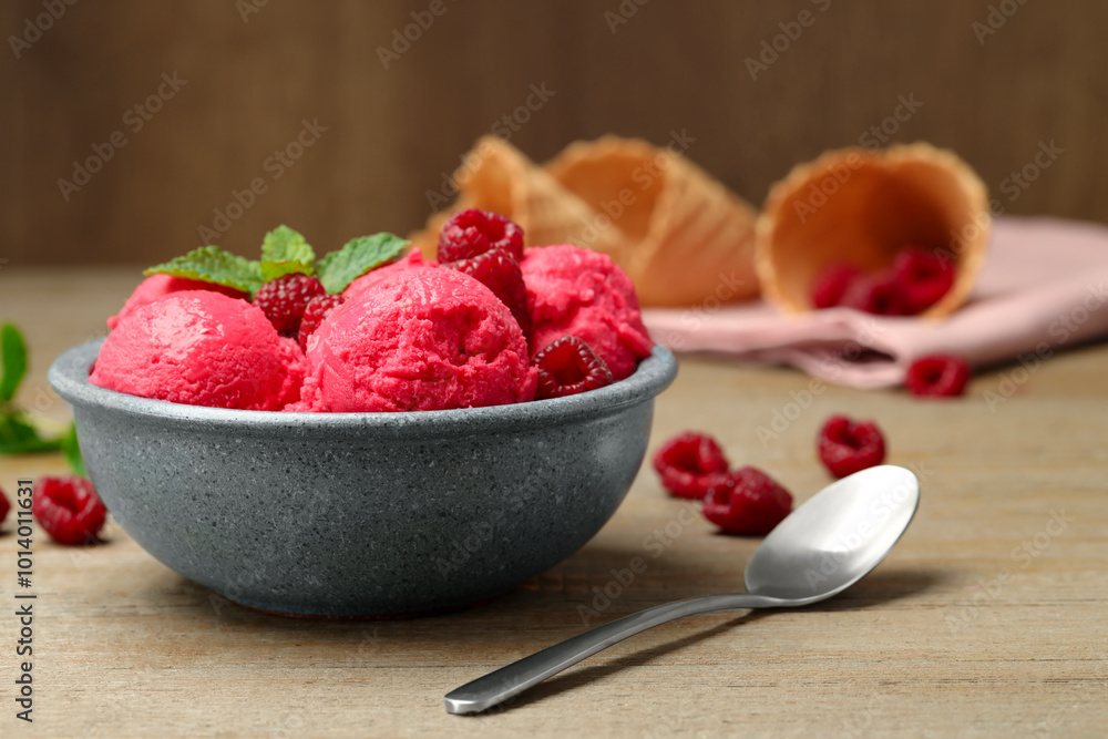 Delicious raspberry sorbet with fresh berries in bowl and spoon on wooden table Delicious raspberry sorbet with fresh berries in bowl and spoon on wooden table