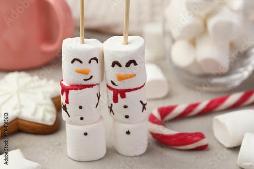 Funny snowmen made of marshmallows and other sweets on light table, closeup