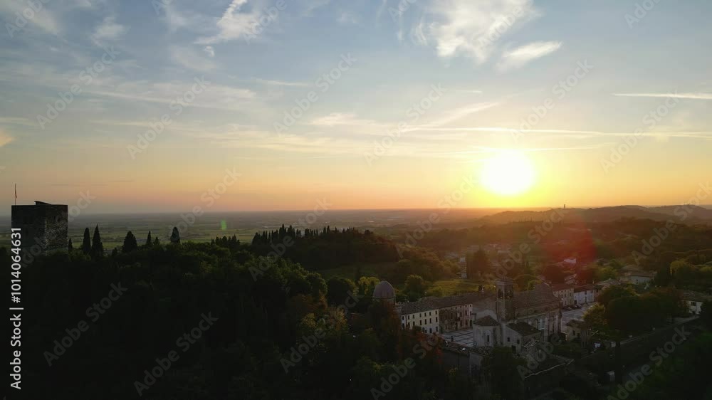 Drone orbits old and historic castle tower, church and piazza on tall tree covered hillside in Solferino, Northern Italy, during sunset. Drone orbits old and historic castle tower, church and piazza on tall tree covered hillside in Solferino, Northern Italy, during sunset.
