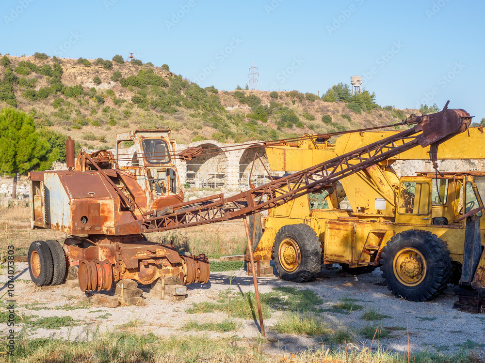 Two rusted, abandoned cranes sit in a deserted field Two rusted, abandoned cranes sit in a deserted field