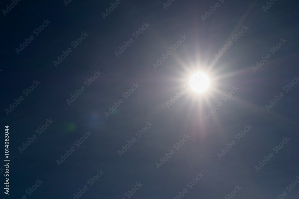 A bright sun is shining through the clouds on a clear day. The sun is the main focus of the image, and the blue sky in the background creates a peaceful and serene atmosphere A bright sun is shining through the clouds on a clear day. The sun is the main focus of the image, and the blue sky in the background creates a peaceful and serene atmosphere