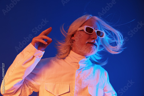 Futuristic man in white jacket with long hair against a blue background, striking a confident pose while wearing stylish sunglasses, embodying a modern and artistic vibe photo