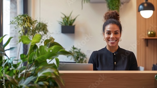 A smiling receptionist greeting visitors in a stylish office lobby with plants and minimalist decor.