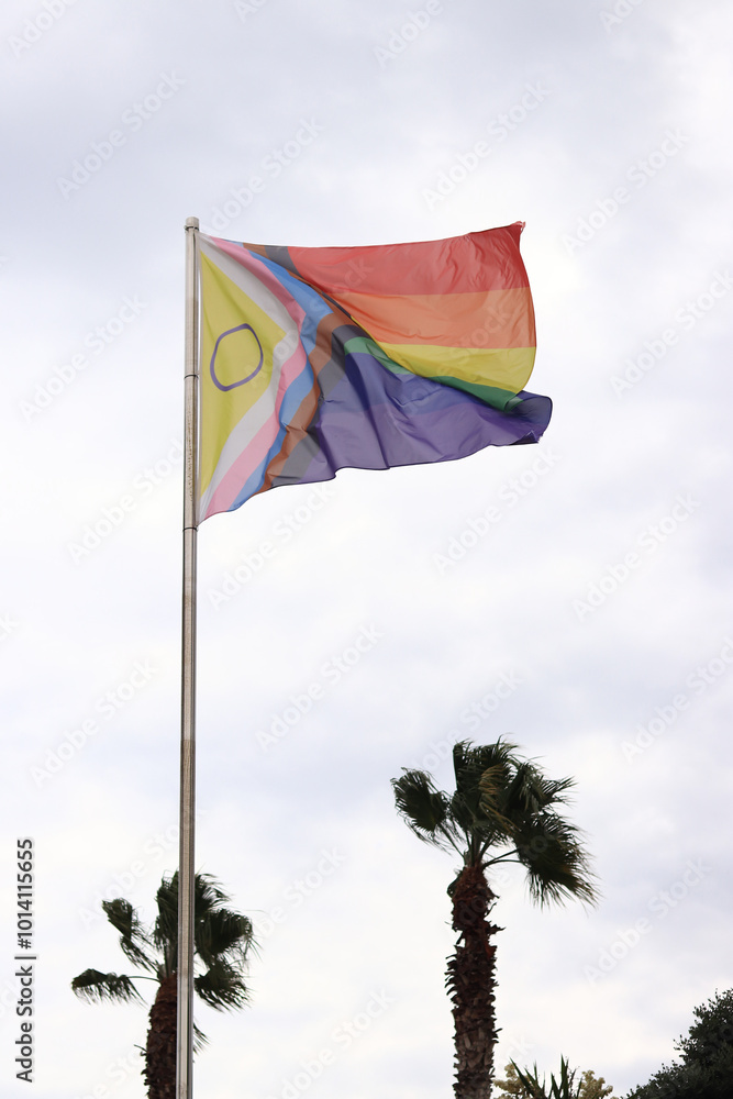 Intersex-inclusive redesign of the Progress Pride Flag. Rainbow LGBT flag against the sky. Flag flutters in the wind in bad weather. Abbreviation that stands for lesbian, gay, bisexual, transgender Intersex-inclusive redesign of the Progress Pride Flag. Rainbow LGBT flag against the sky. Flag flutters in the wind in bad weather. Abbreviation that stands for lesbian, gay, bisexual, transgender