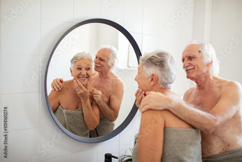 Elderly couple examining their skin in bathroom mirror photo