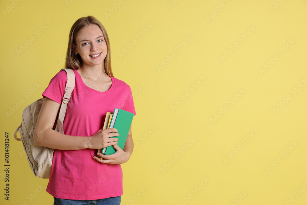 Teenage girl with books and backpack on yellow background, space for text Teenage girl with books and backpack on yellow background, space for text