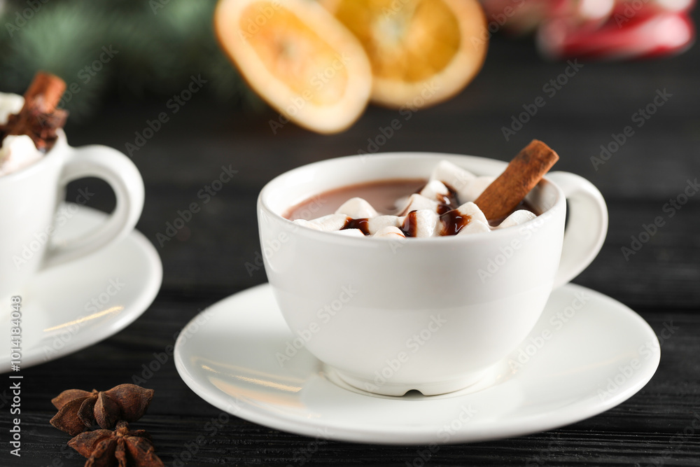 Tasty hot cocoa drink with marshmallows in cups and spices on black wooden table, closeup Tasty hot cocoa drink with marshmallows in cups and spices on black wooden table, closeup