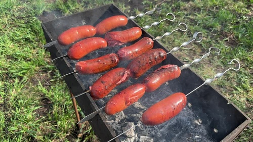 Succulent sausages are carefully arranged on metal skewers and slowly roasted over the glowing embers of the outdoor barbecue.