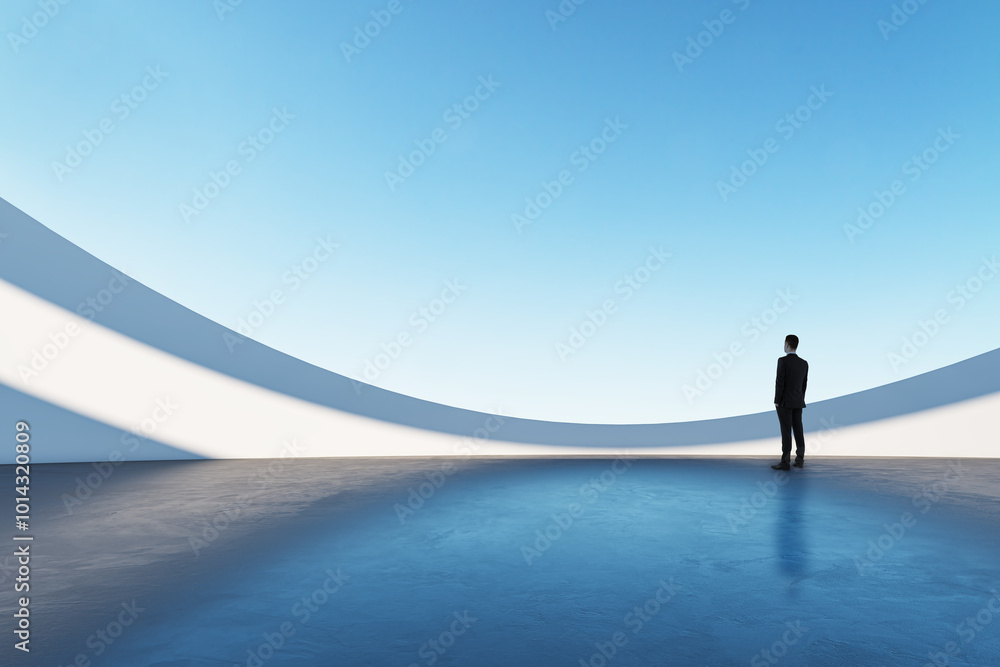 © Who is Danny - Businessman standing in a futuristic, minimalistic architectural space with blue sky and curved white walls.