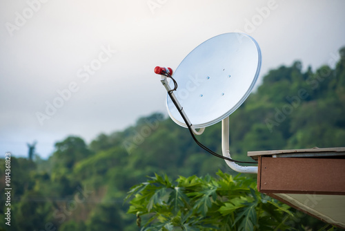 Satellite Dish on Rooftop with Greenery Background. photo