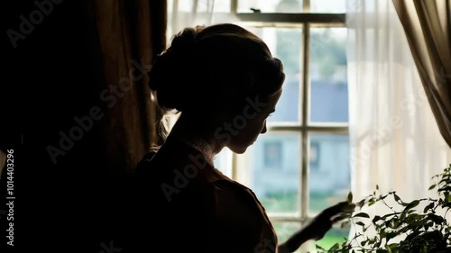 A woman in Victorian dress taking care of her plants by a window