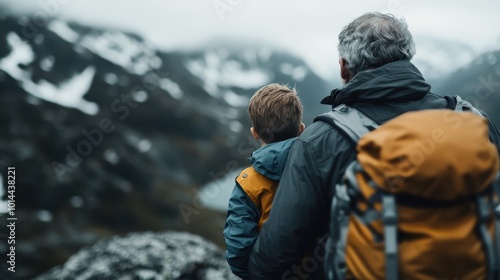 An older man and young boy stand side by side, overlooking a picturesque mountain view, symbolizing a shared moment of introspection and connection.