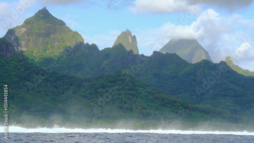 Scenic view of Moorea Island in Tahiti, French Polynesia, with ocean waves breaking over coral reef and rugged mountainous landscape