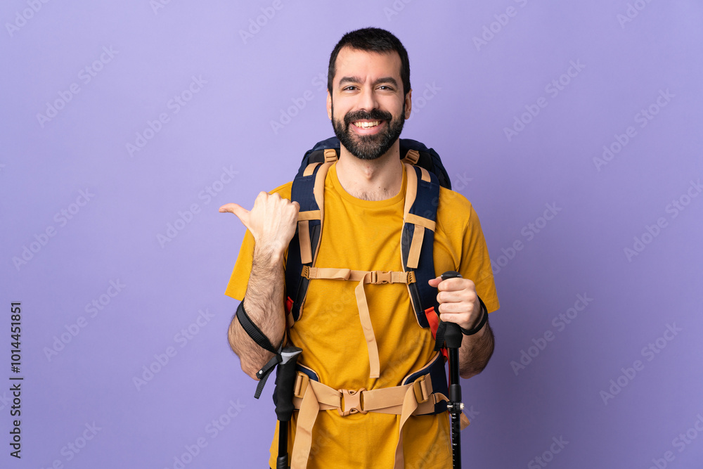 Caucasian handsome man with backpack and trekking poles over isolated background pointing to the side to present a product Caucasian handsome man with backpack and trekking poles over isolated background pointing to the side to present a product