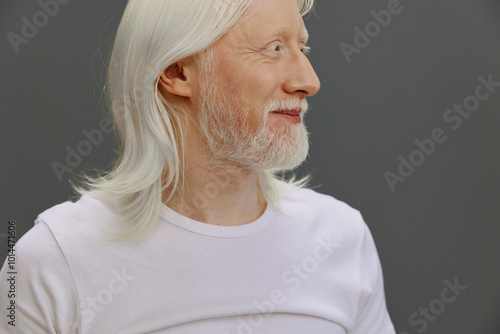 elderly man with long white hair and beard, profile view, neutral gray background, serene expression, wearing a plain white shirt showcasing wisdom and tranquility in his appearance photo