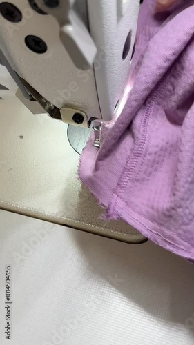 A female seamstress sews a skirt, corduroy trousers, velour, a fashion expert, a fashion factory or studio, an atelier, a vision of a design startup. Vertical video.