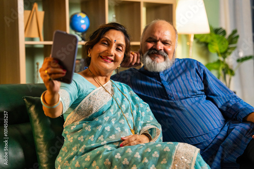 Canvas Print Asian Indian elderly couple enjoying a fun selfie together in their modern home