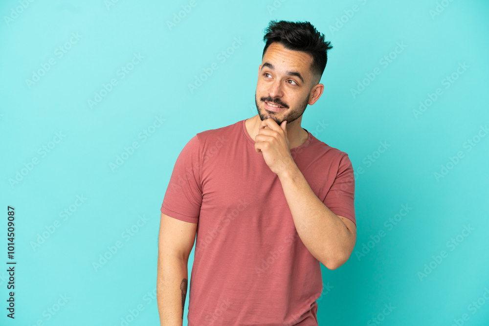 Young caucasian man isolated on blue background looking up while smiling Young caucasian man isolated on blue background looking up while smiling