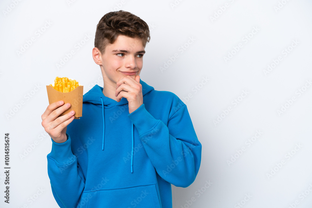 Teenager Russian man holding fried potatoes isolated on white background looking to the side and smiling Teenager Russian man holding fried potatoes isolated on white background looking to the side and smiling