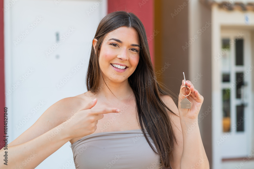 girl holding home keys at outdoors and pointing it girl holding home keys at outdoors and pointing it