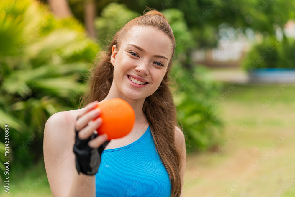 Young pretty sport girl holding an orange at outdoors with happy expression Young pretty sport girl holding an orange at outdoors with happy expression
