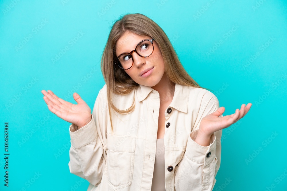 Young caucasian woman isolated on blue background With glasses and having doubts Young caucasian woman isolated on blue background With glasses and having doubts