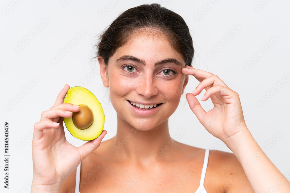 Young Pretty caucasian woman isolated on white background holding an avocado while smiling. Close up portrait Young Pretty caucasian woman isolated on white background holding an avocado while smiling. Close up portrait