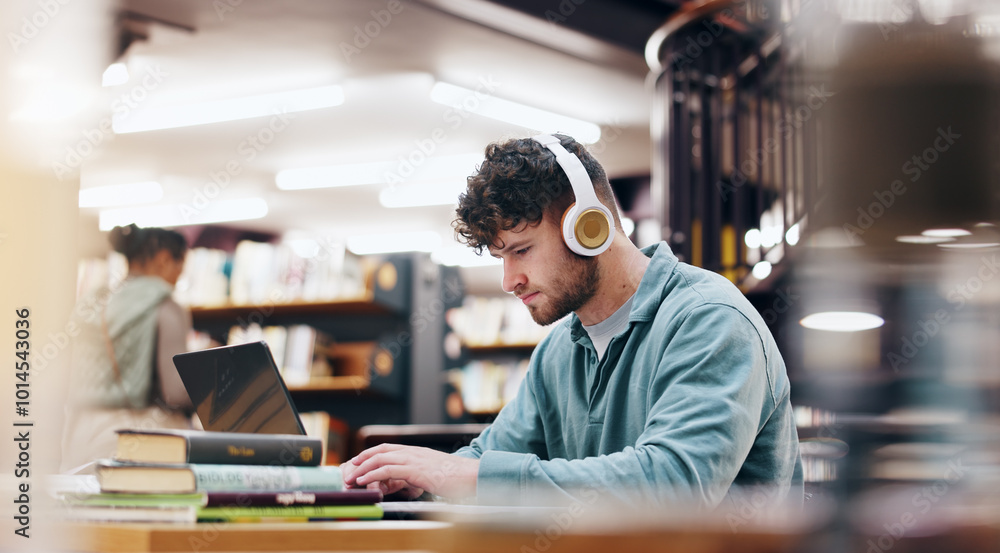 Fototapeta premium Man, student and typing on laptop in library for research information, university website and study schedule. Person, online course and headphones of education project, exam results and podcast audio